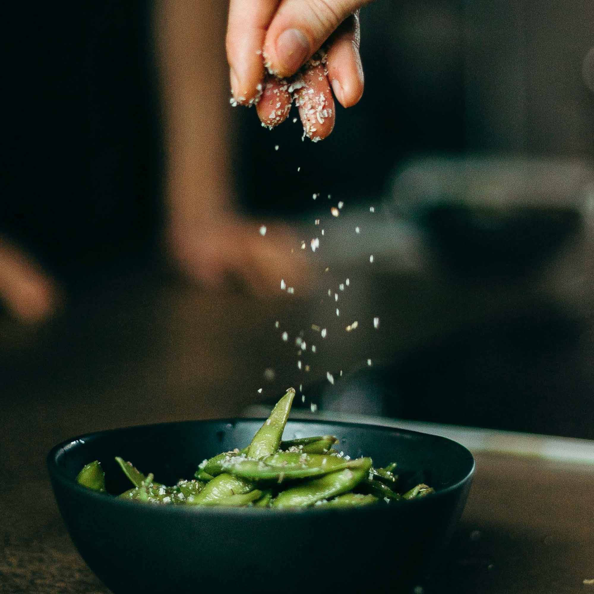 Influencer - Hand streut Gewürz auf Schoten